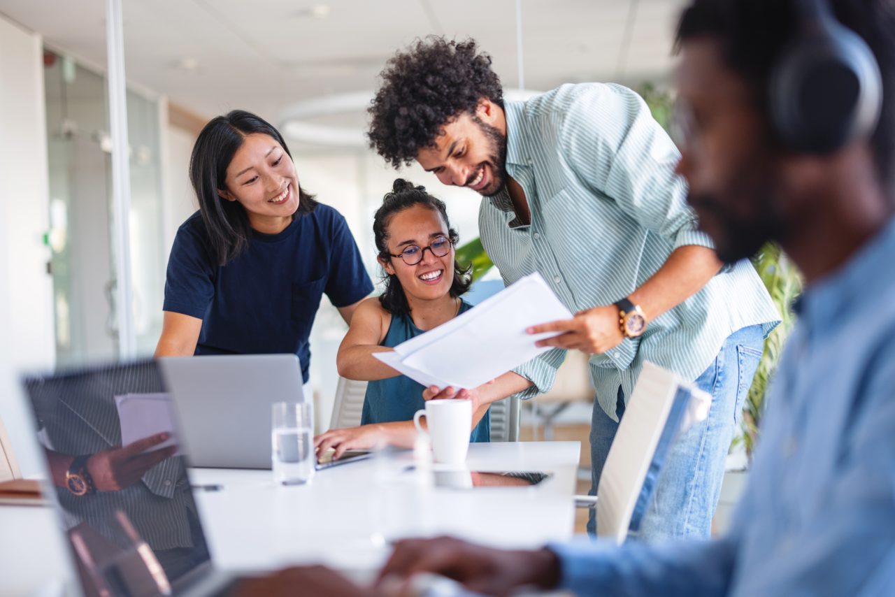 group of colleagues looking at a paper and smiling