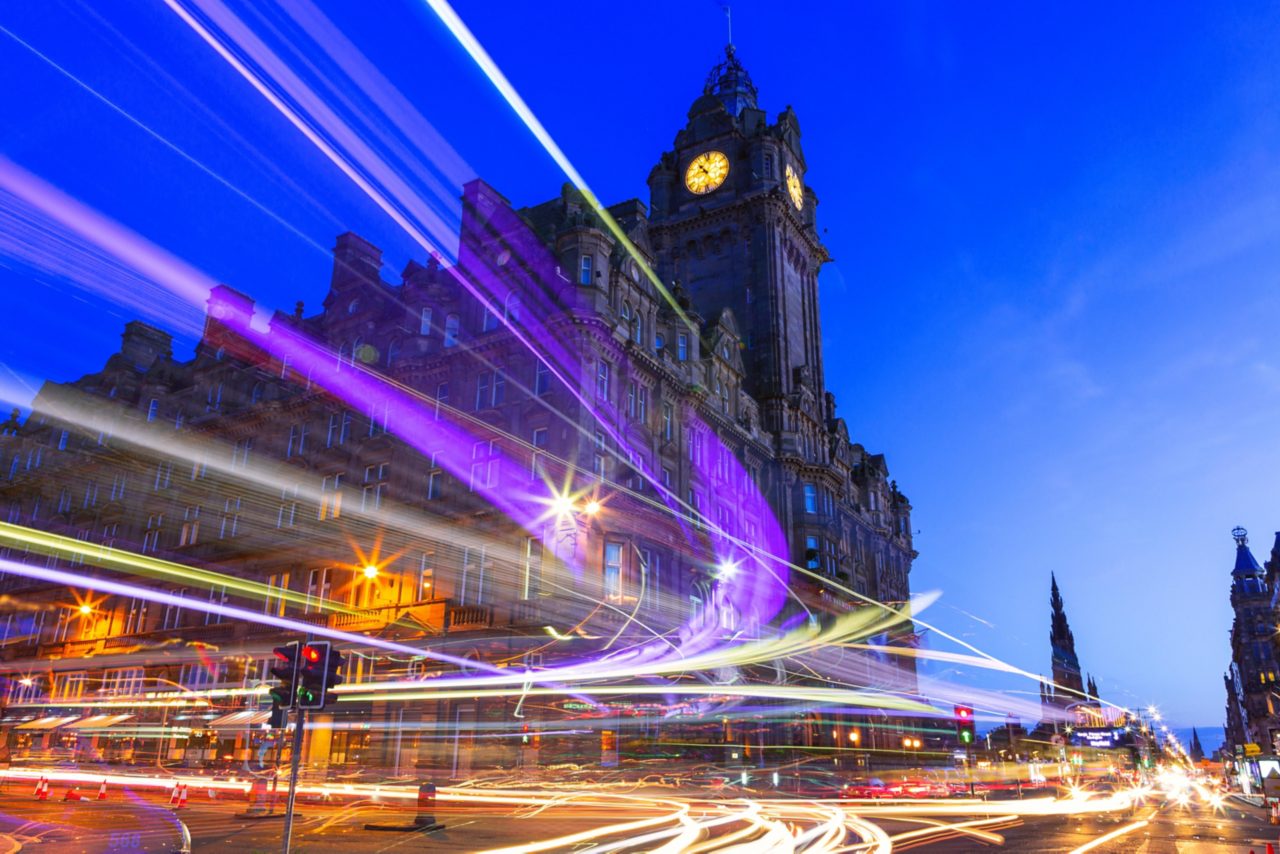 Edinburgh at night scene with Lights streak from high-sided vehicles on Princess street and Balmoral hotel on background