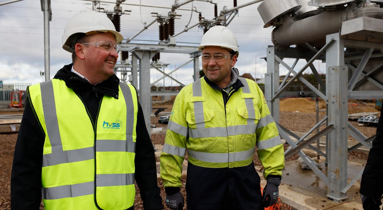 This image shows two men wearing high visibility jackets and hard hats. 