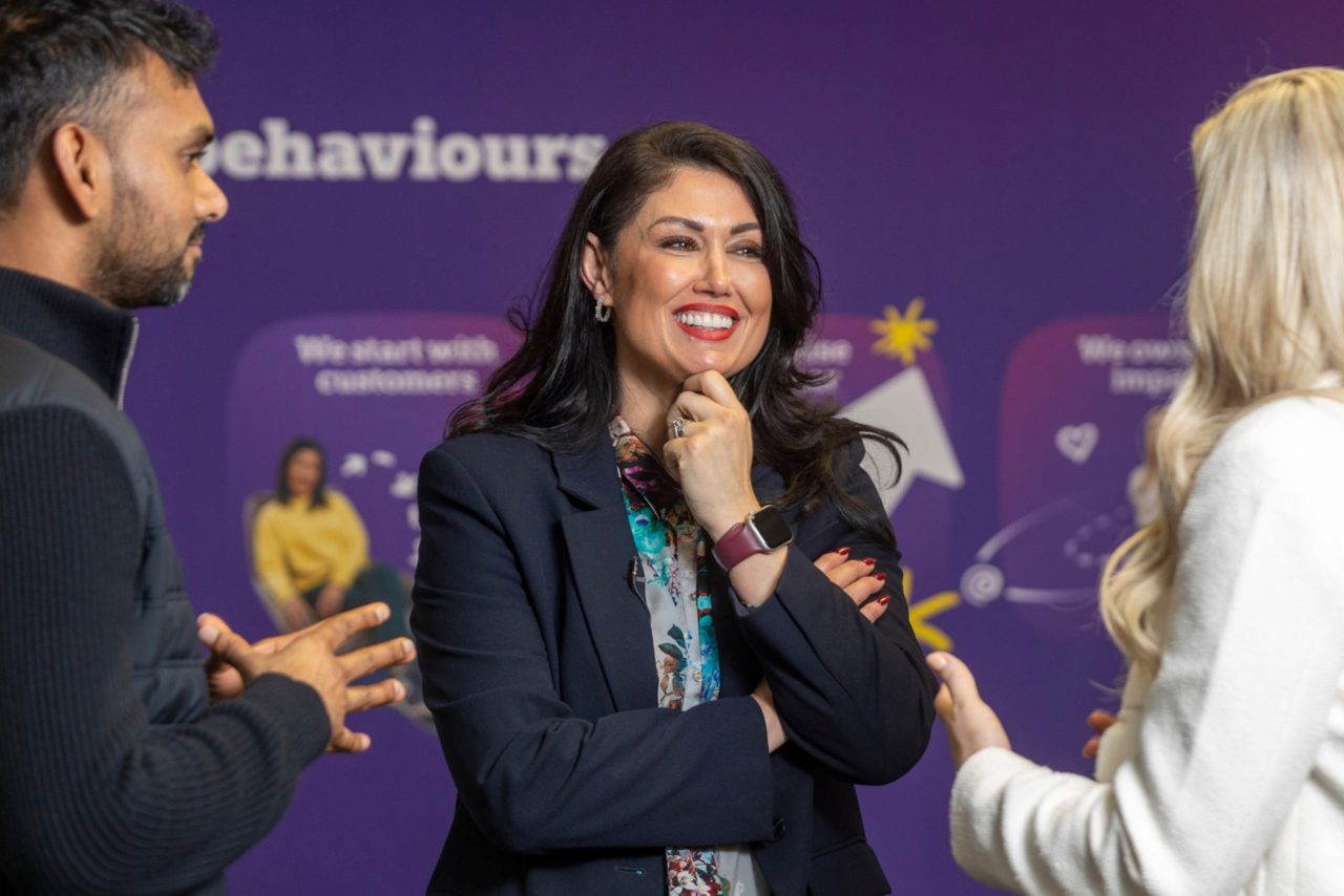 This image shows a two women talking to a man. They are all standing up.