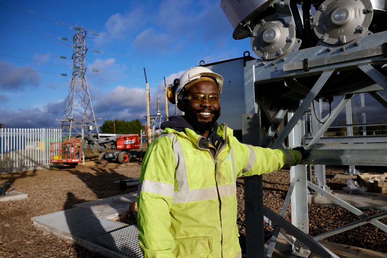 Image of a man in a high-vis jacket and hard hat smiling, looking at the camera