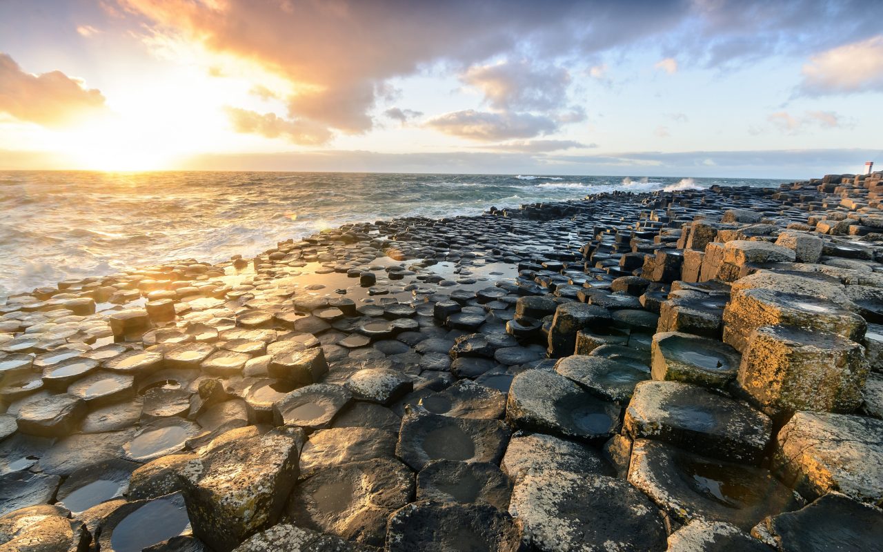 Sun breaking through the clouds on a rocky beach in Northern Ireland