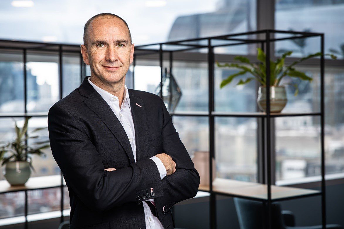 This image shows NatWest Group’s Chief Information Officer, Scott Marcar standing, looking to camera with his arms crossed. 