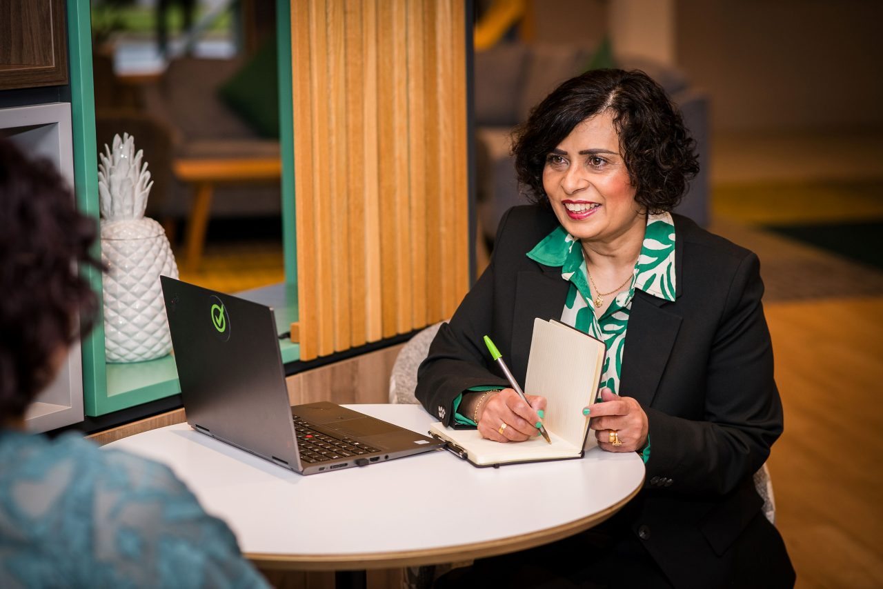 This image shows a woman with an open laptop and notepad