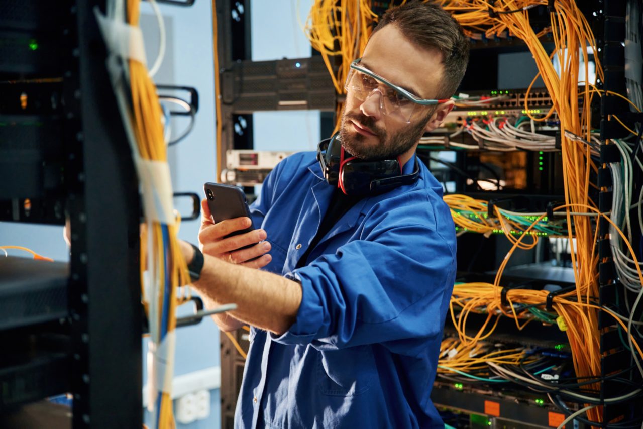 This image shows a man standing next to a data server, working on the equipment