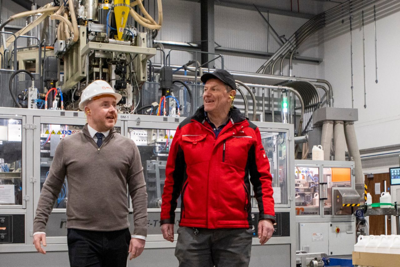 this images shows two men walking across a factory floor 