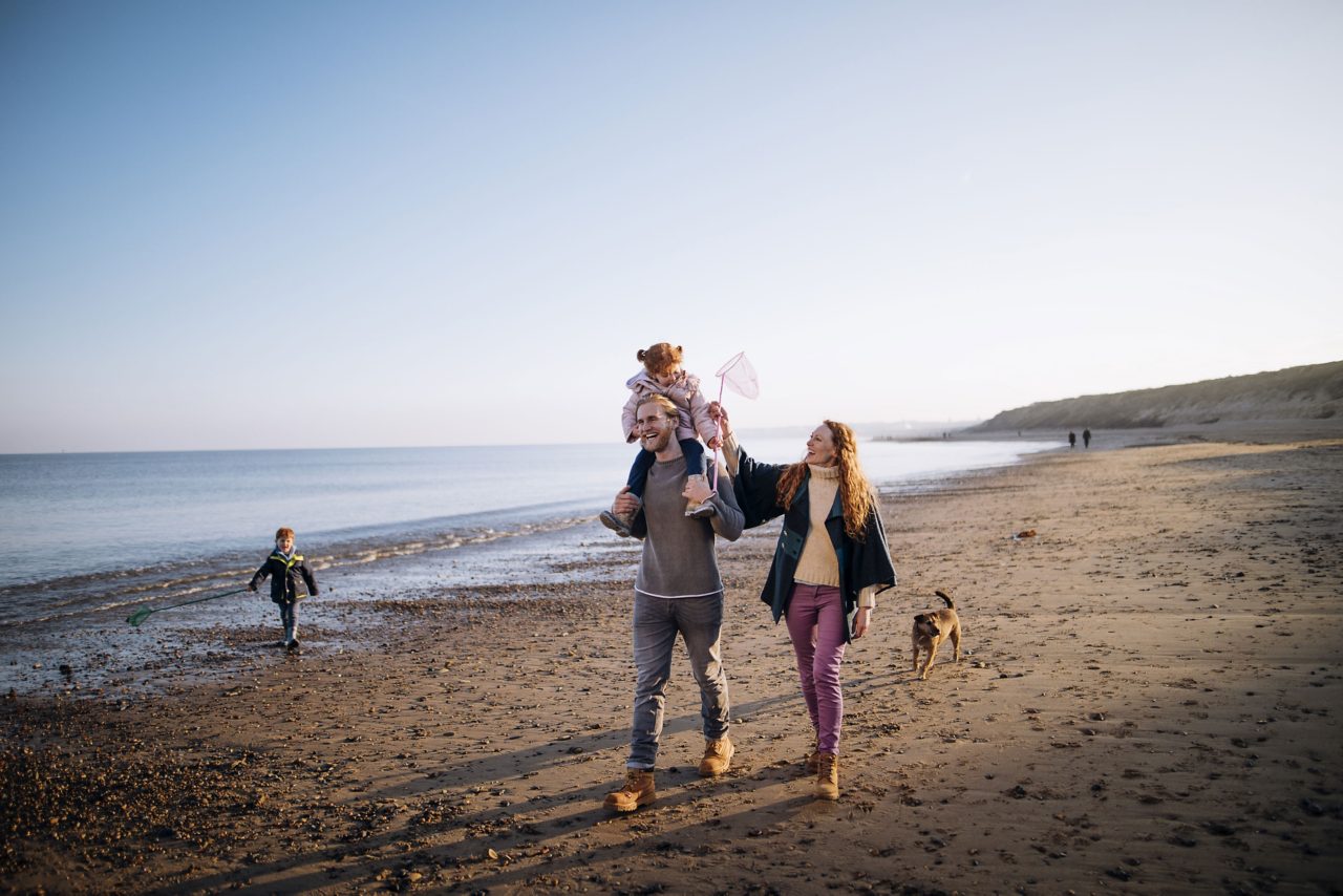 Photo of family and dog walking on beach