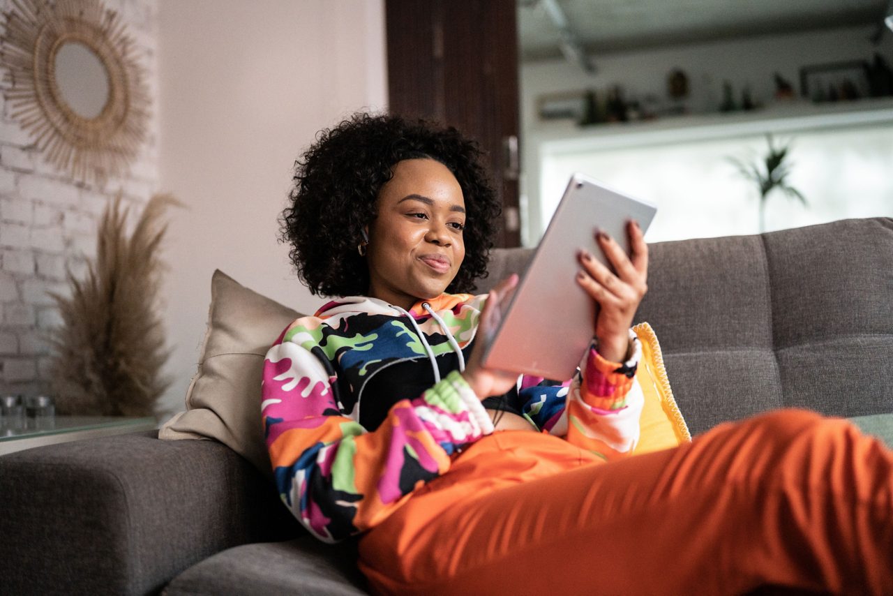 Woman sitting on sofa viewing tablet