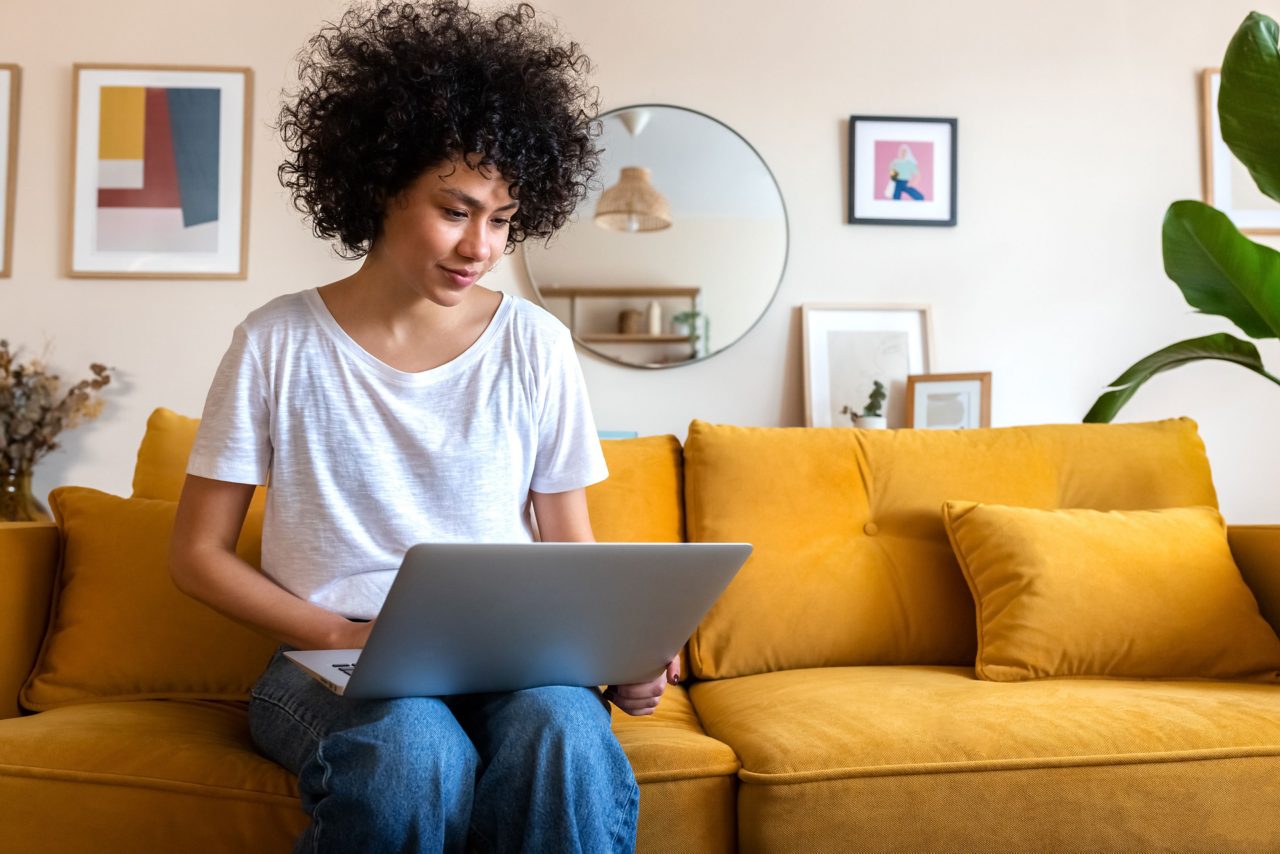 Woman sitting on sofa using her laptop