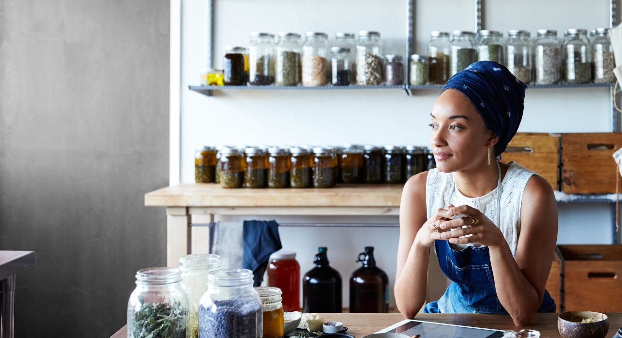 Photo of a person sitting in front of jars on a shelf